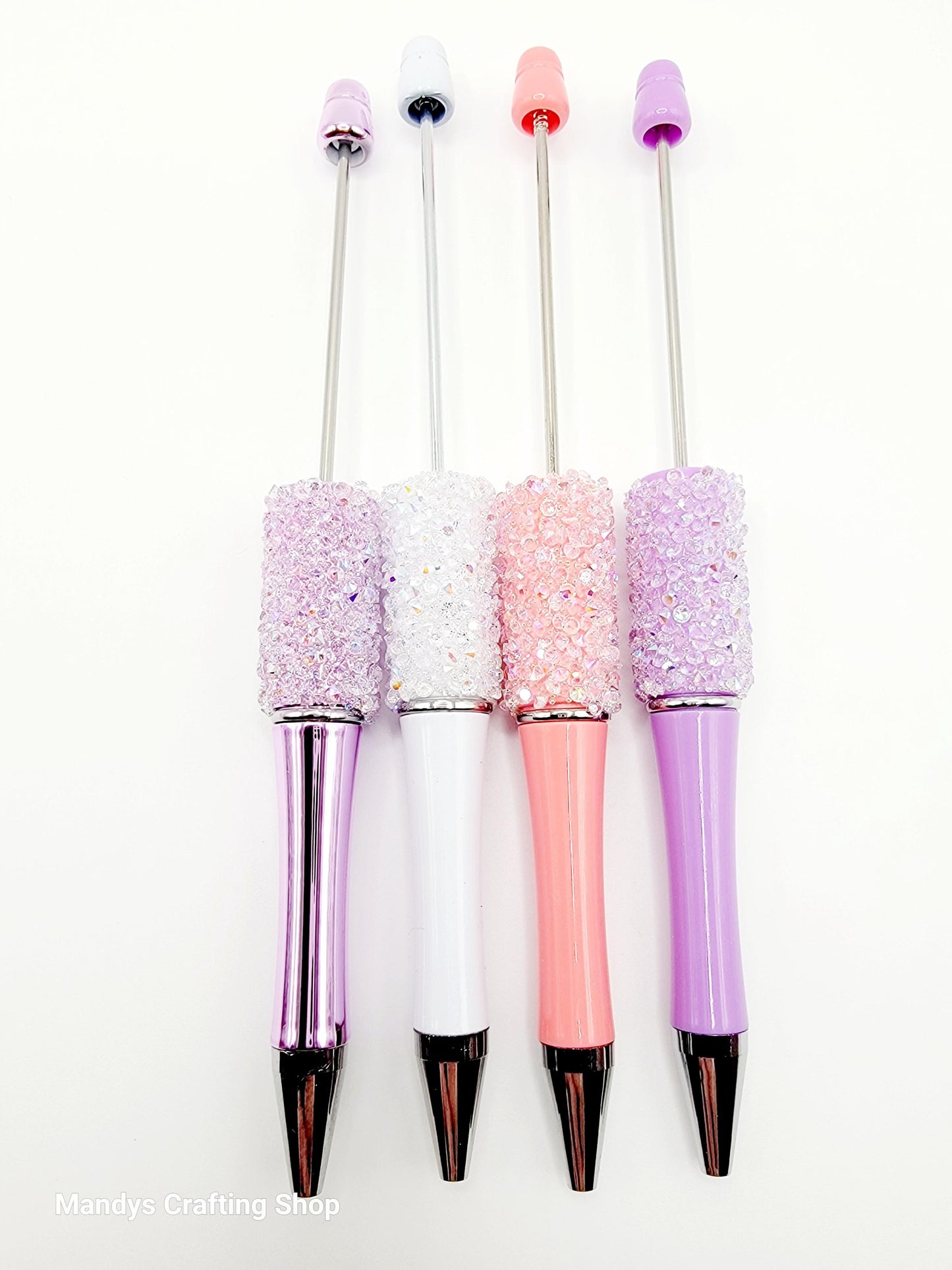 Four decorative pens with glittery accents on a white background