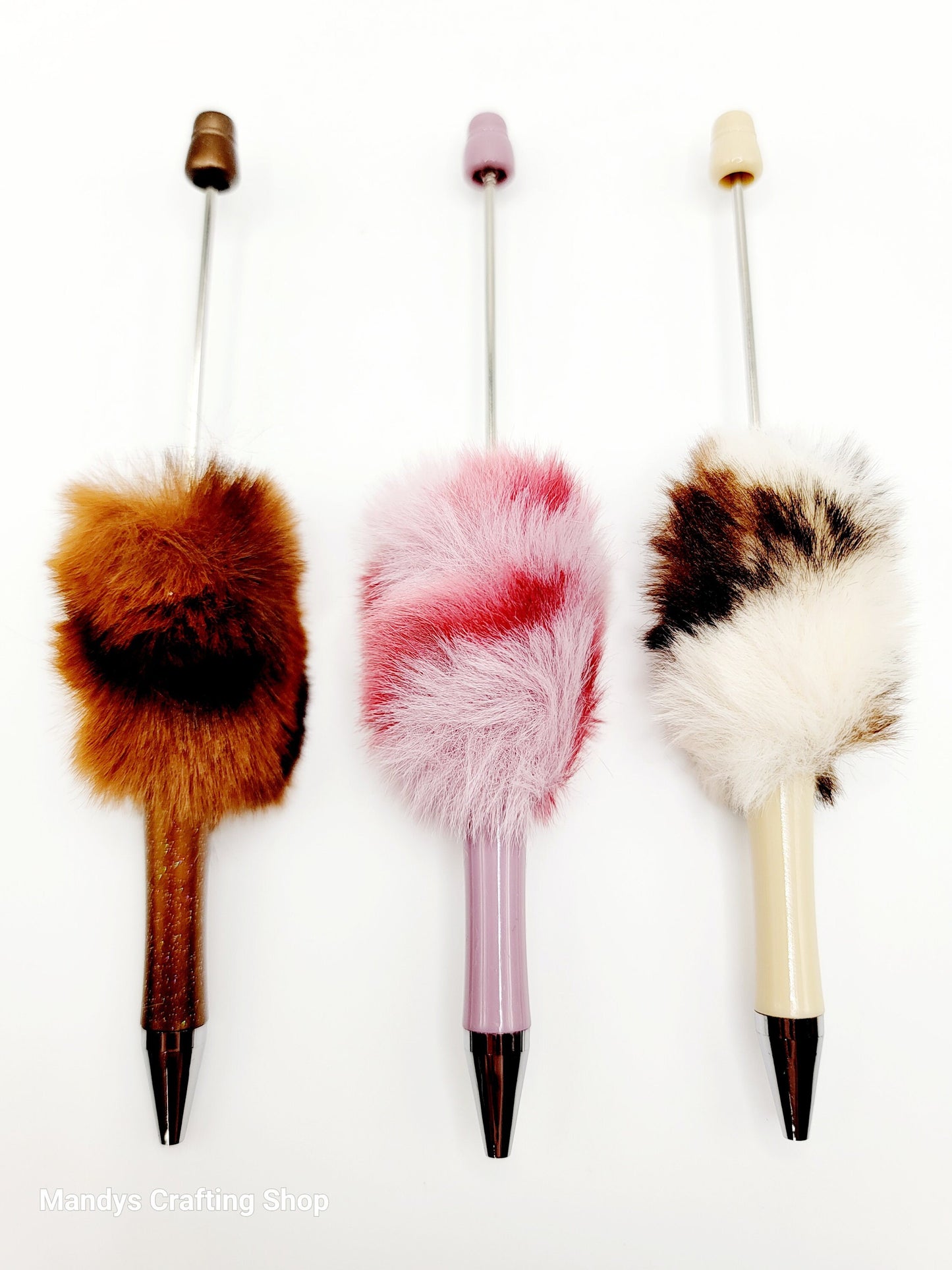 Three decorative pens with fur accents on a white background