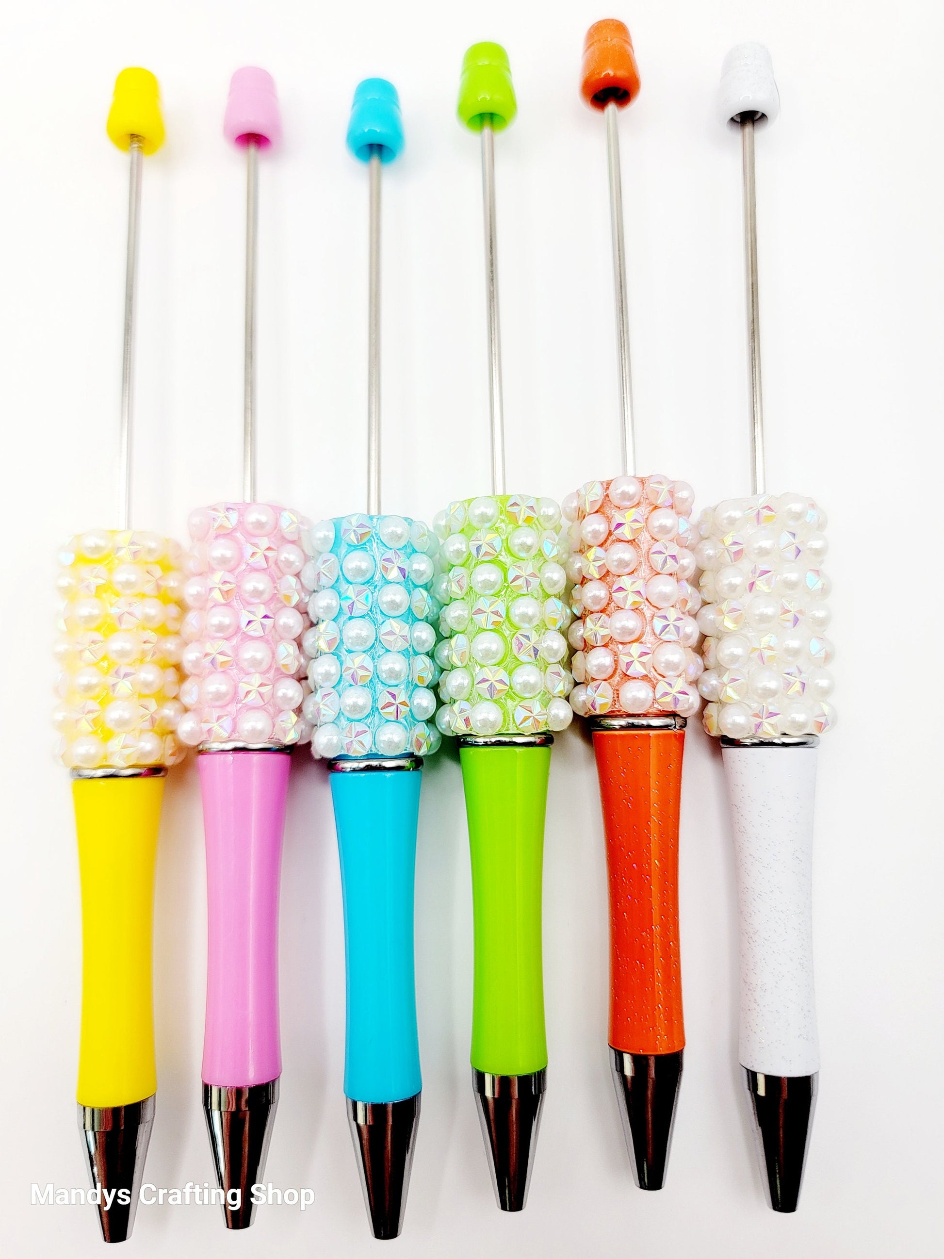 Set of colorful pens with decorative bead accents on a white background