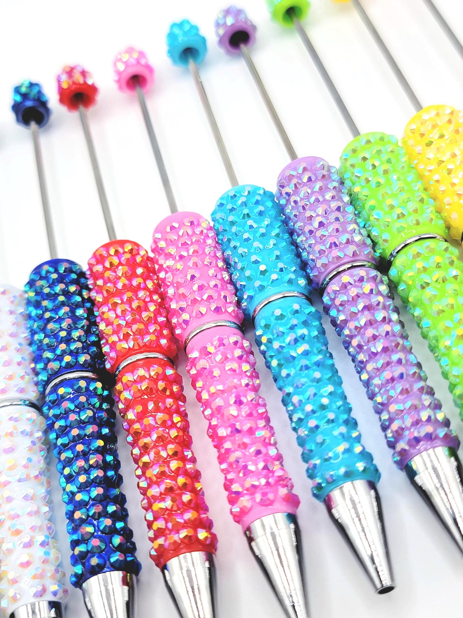 Colorful rhinestone-handled pens on a white background