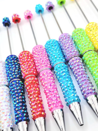 Colorful rhinestone-handled pens on a white background