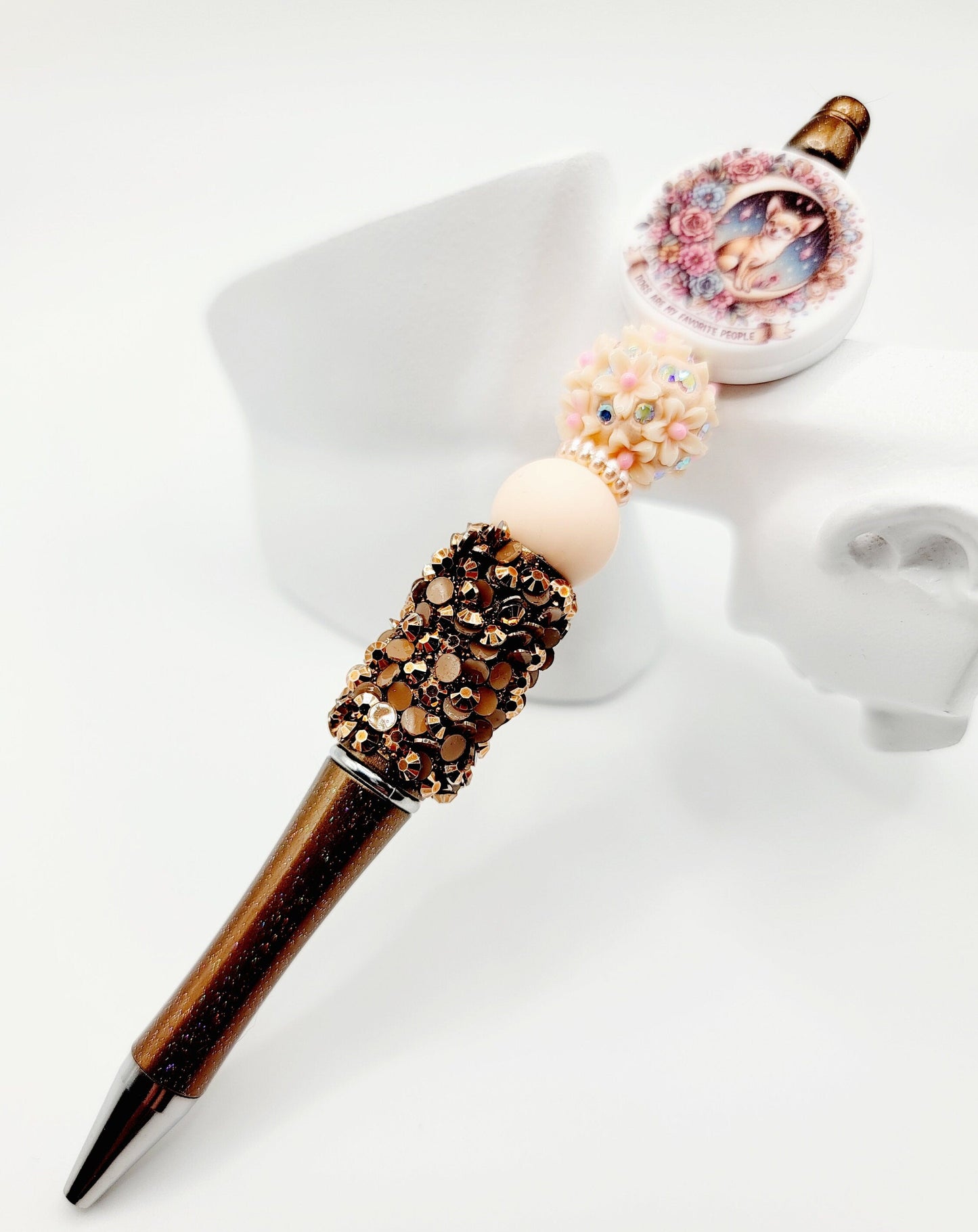 Decorative pen with gemstone accents and a photo charm on a white background