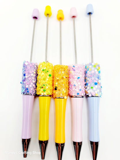 Five colorful pens with glittery accents on a white background