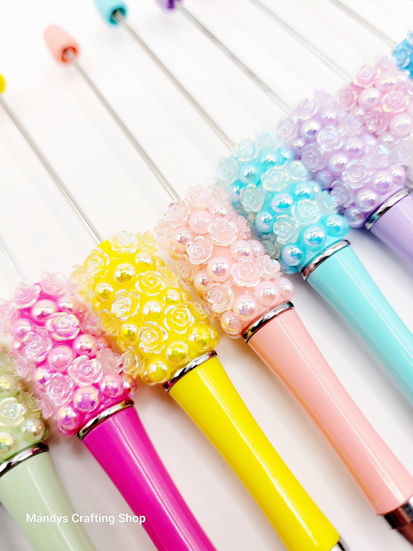 Colorful pens with decorative beads on a white background
