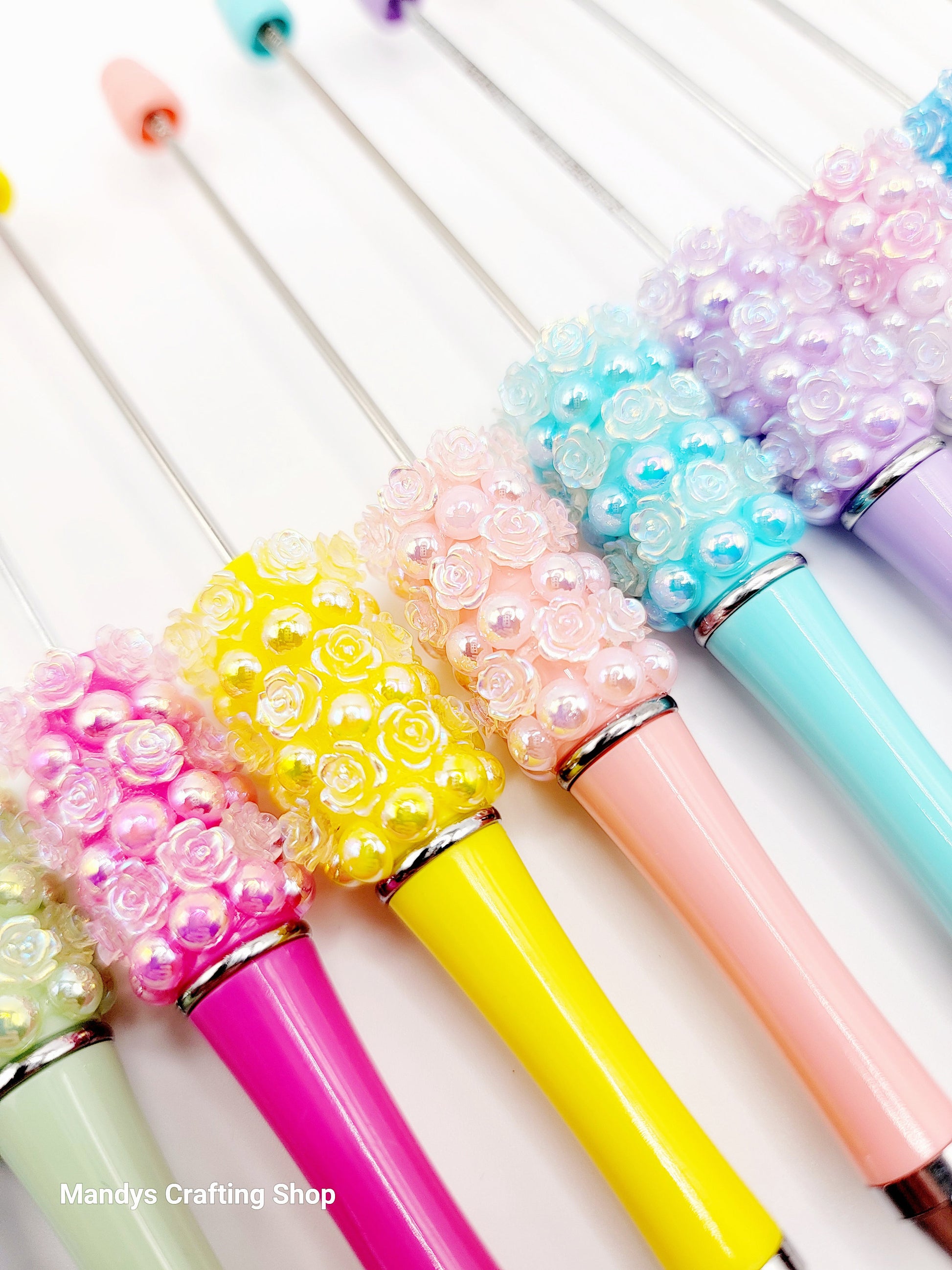 Colorful pens with decorative beads on a white background