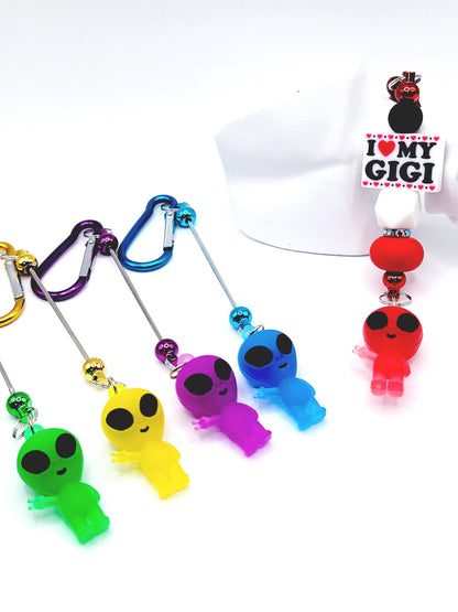 Colorful alien-shaped keychains with carabiners on a white background