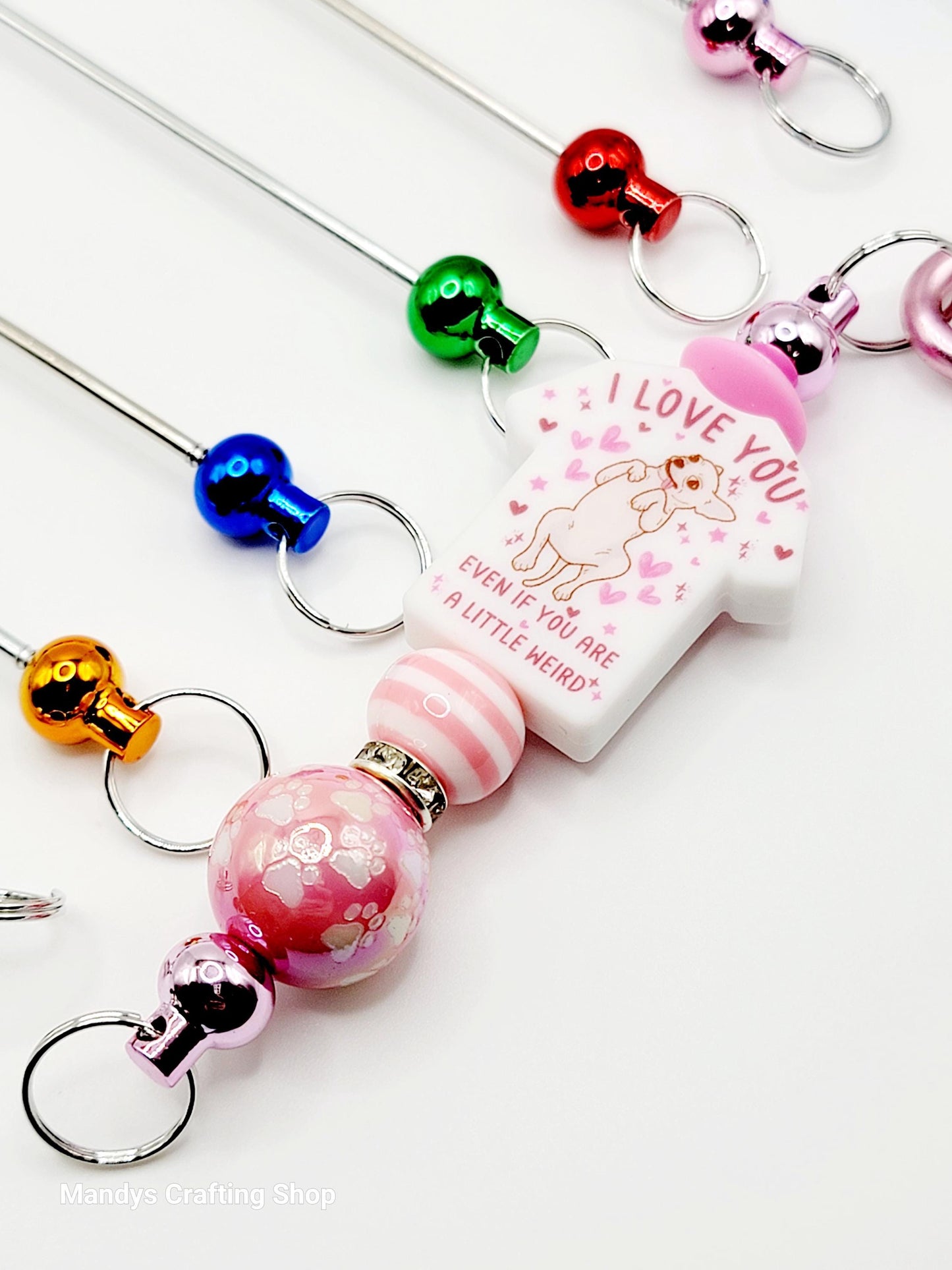Colorful keychains with various designs and text on a white background