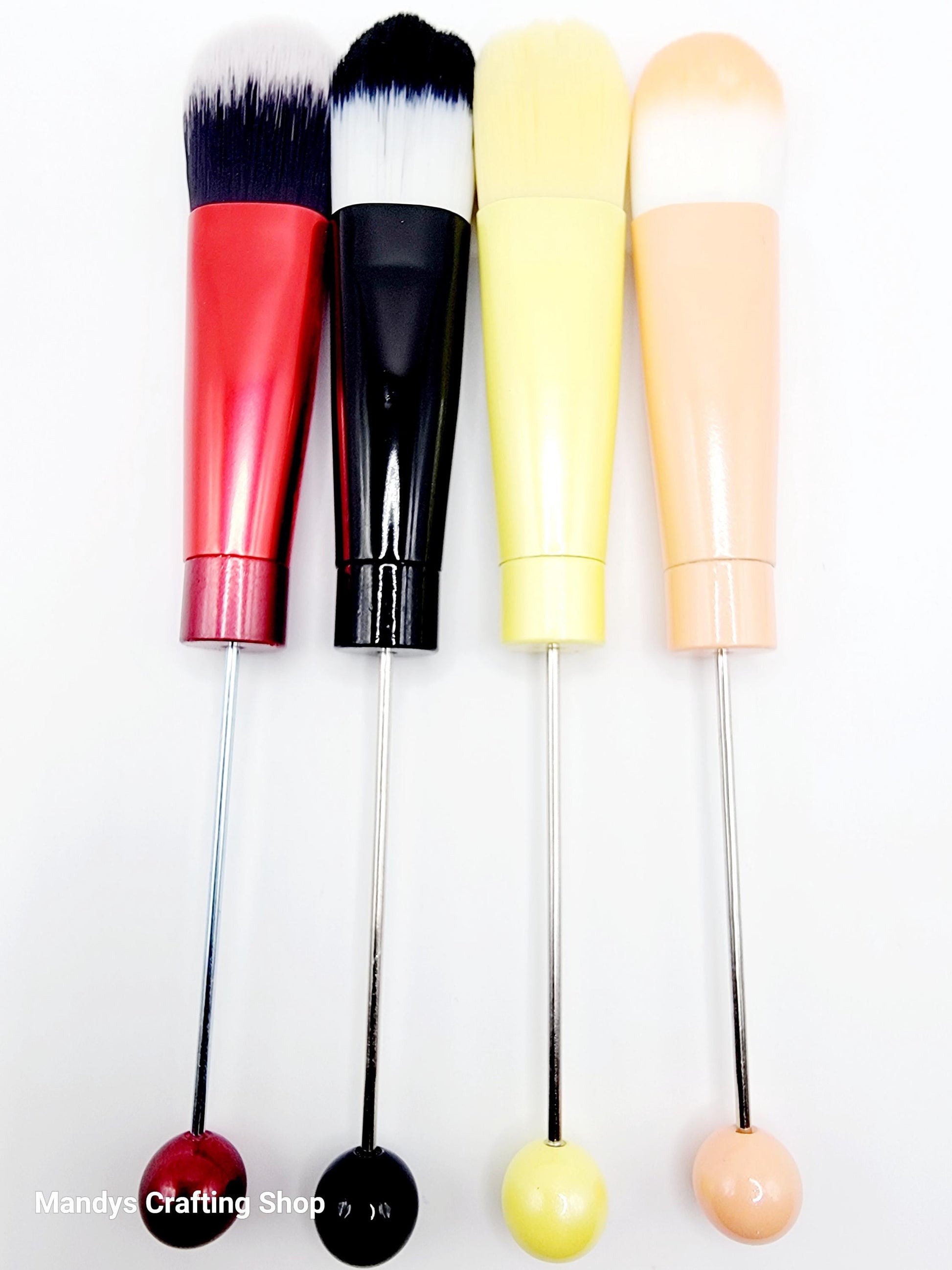 Set of four makeup brushes with colorful handles on a white background