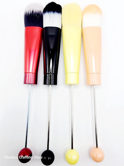 Set of four makeup brushes with colorful handles on a white background