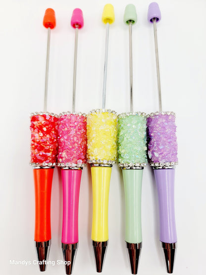 Five colorful pens with decorative caps on a white background