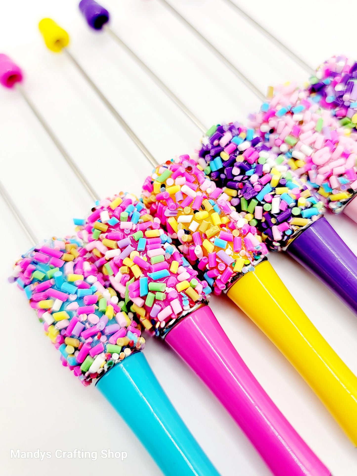 Colorful pens with sprinkles on a white background