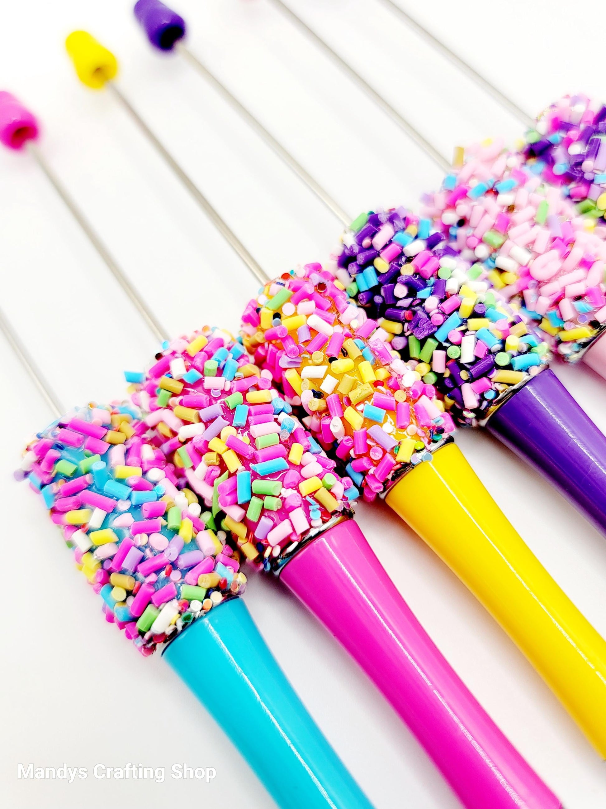Colorful pens with sprinkles on a white background