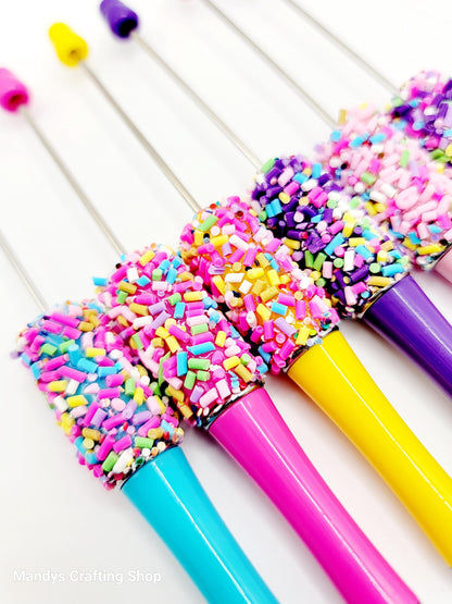 Colorful pens with sprinkles on a white background