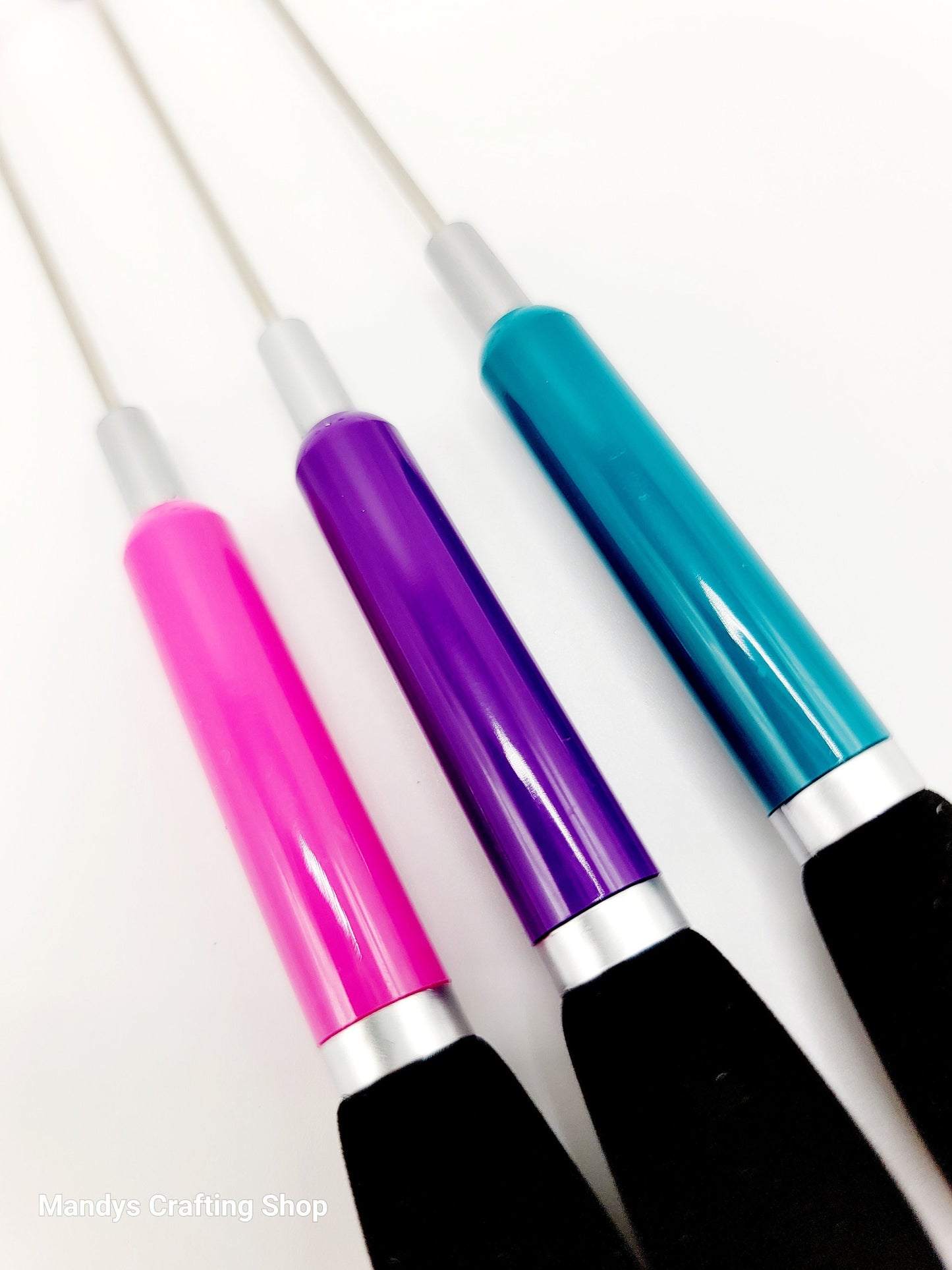 Three colorful pens with pink, purple, and blue handles on a white background.