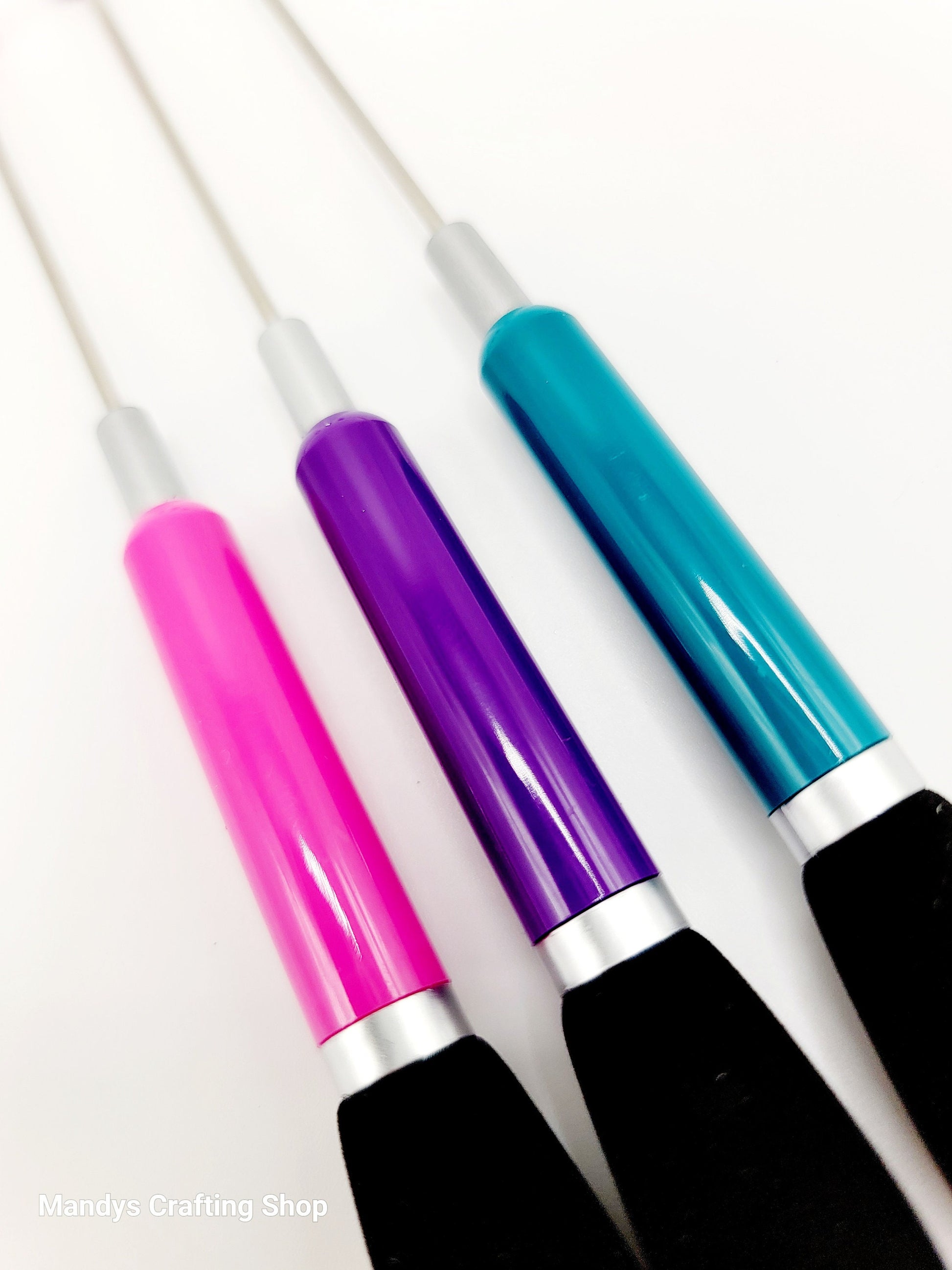 Three colorful pens with pink, purple, and blue handles on a white background.