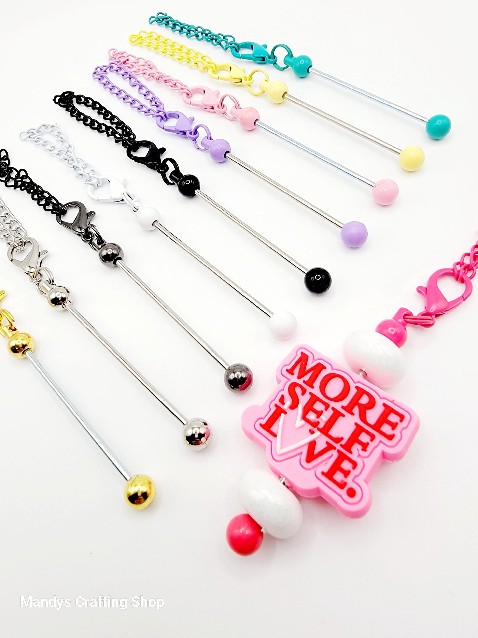 Set of colorful jewelry items with a pink tag reading 'More Self Love' on a white background.