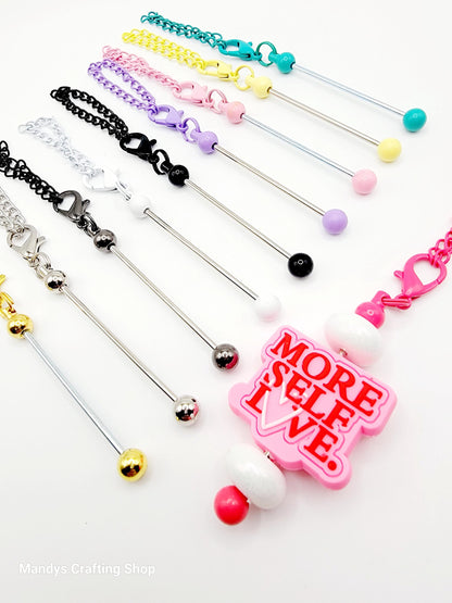 Set of colorful jewelry items with a pink tag reading 'More Self Love' on a white background.