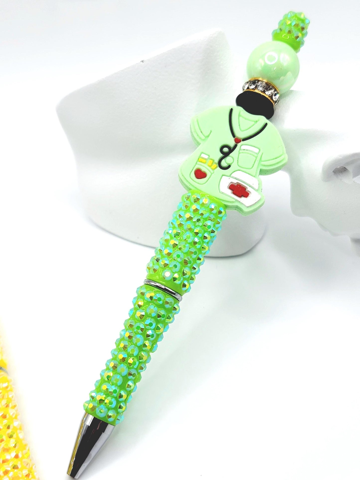 Decorative pen with green gemstones on a white background