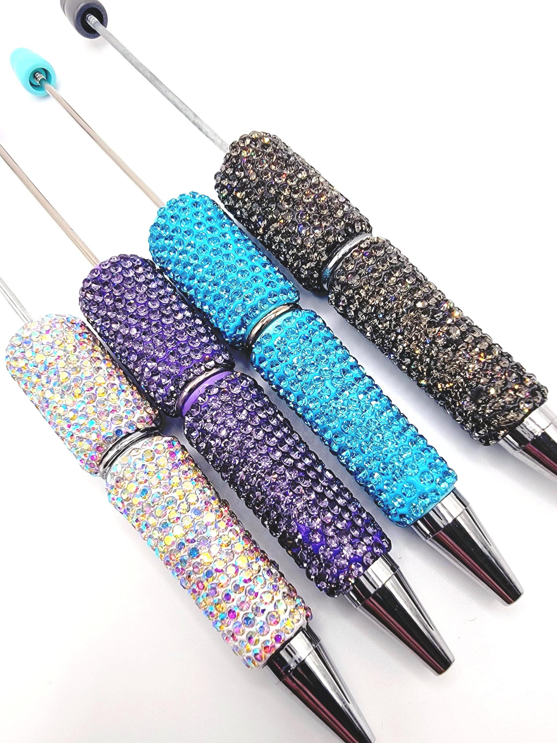 Set of four glittery pens with different color schemes on a white background