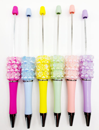 Set of colorful pens with decorative beads on a white background