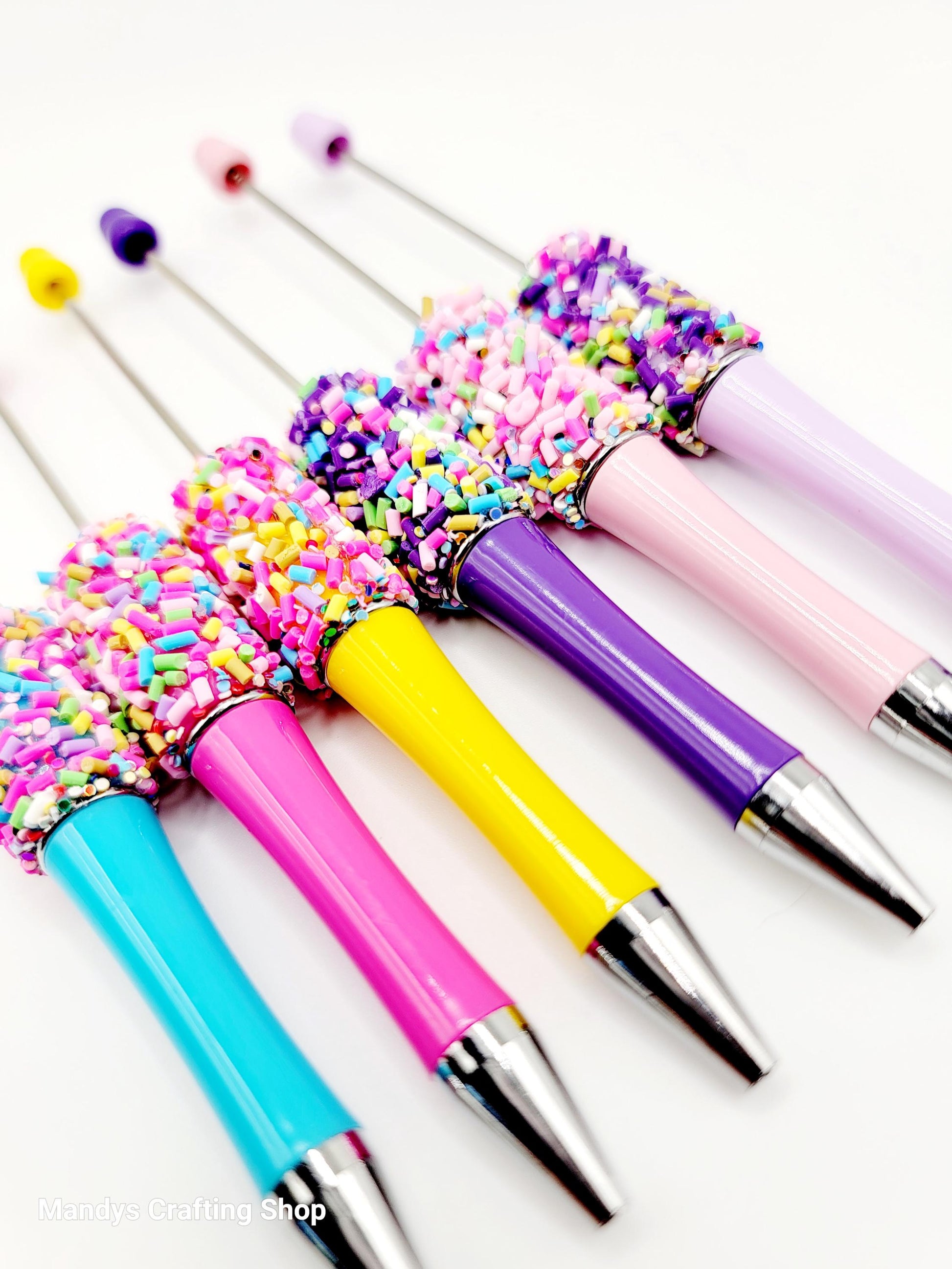 Colorful pens with sprinkles on a white background