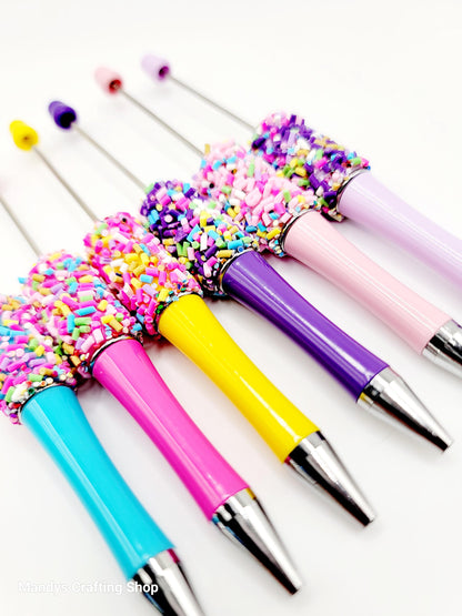 Colorful pens with sprinkles on a white background
