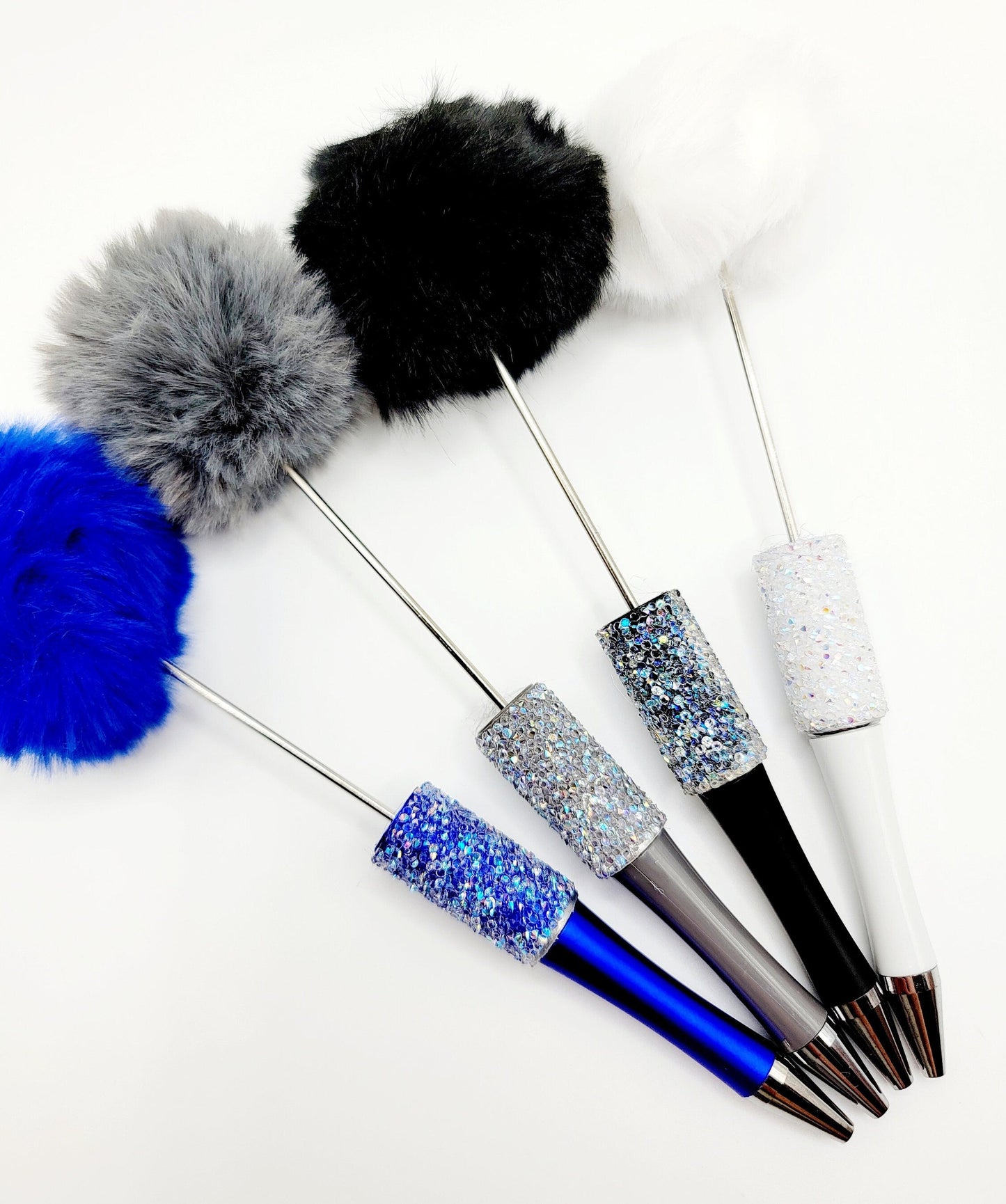 Decorative pens with glittery accents and pom-pom ends on a white background