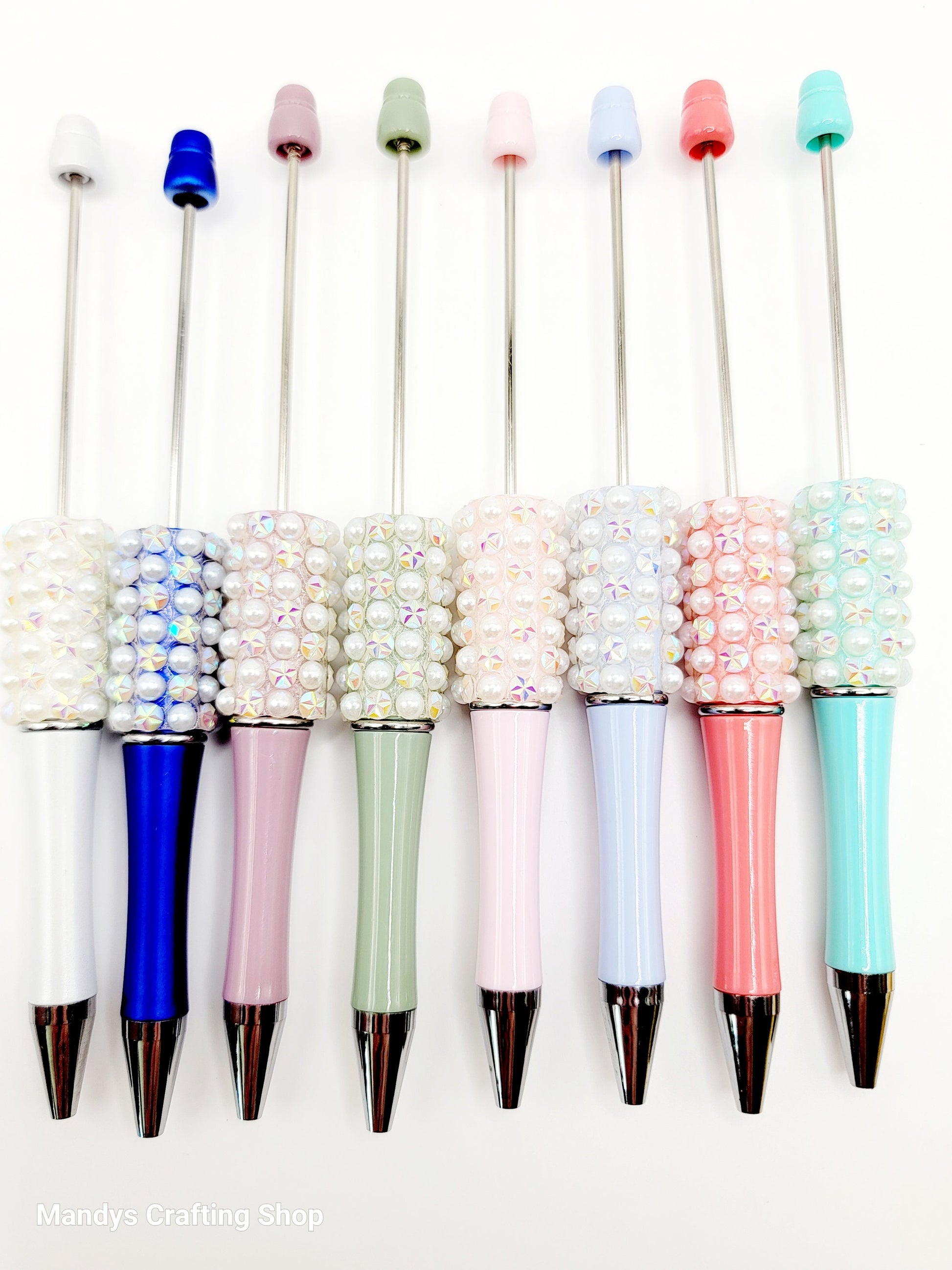 Set of colorful pens with decorative bead accents on a white background
