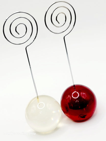 Decorative ornament with white and red glass balls on metal spiral stands against a white background.
