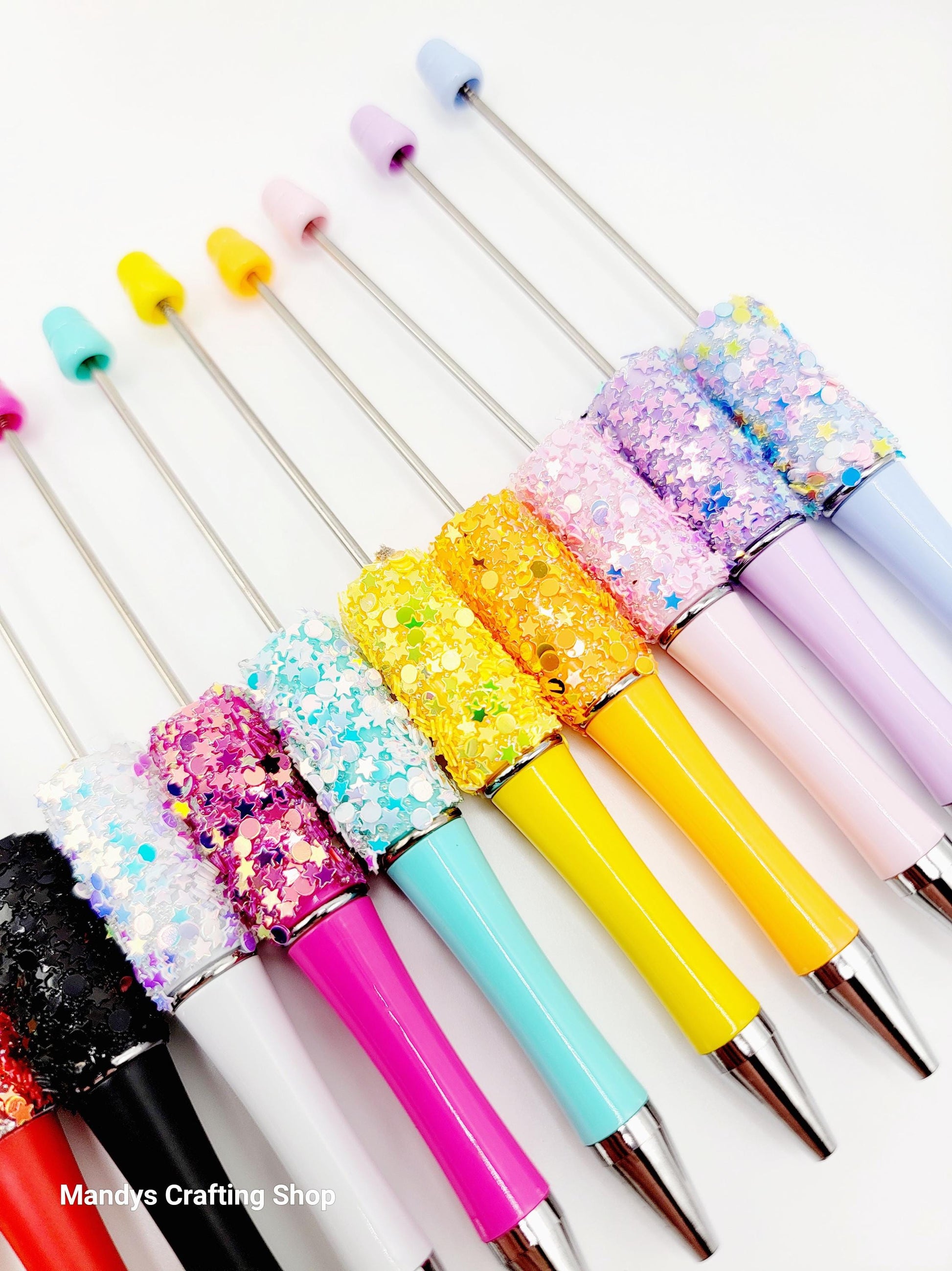 Colorful glittery pens with various designs on a white background