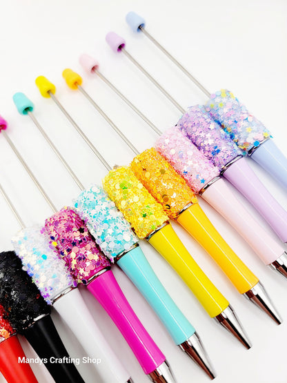 Colorful glittery pens with various designs on a white background