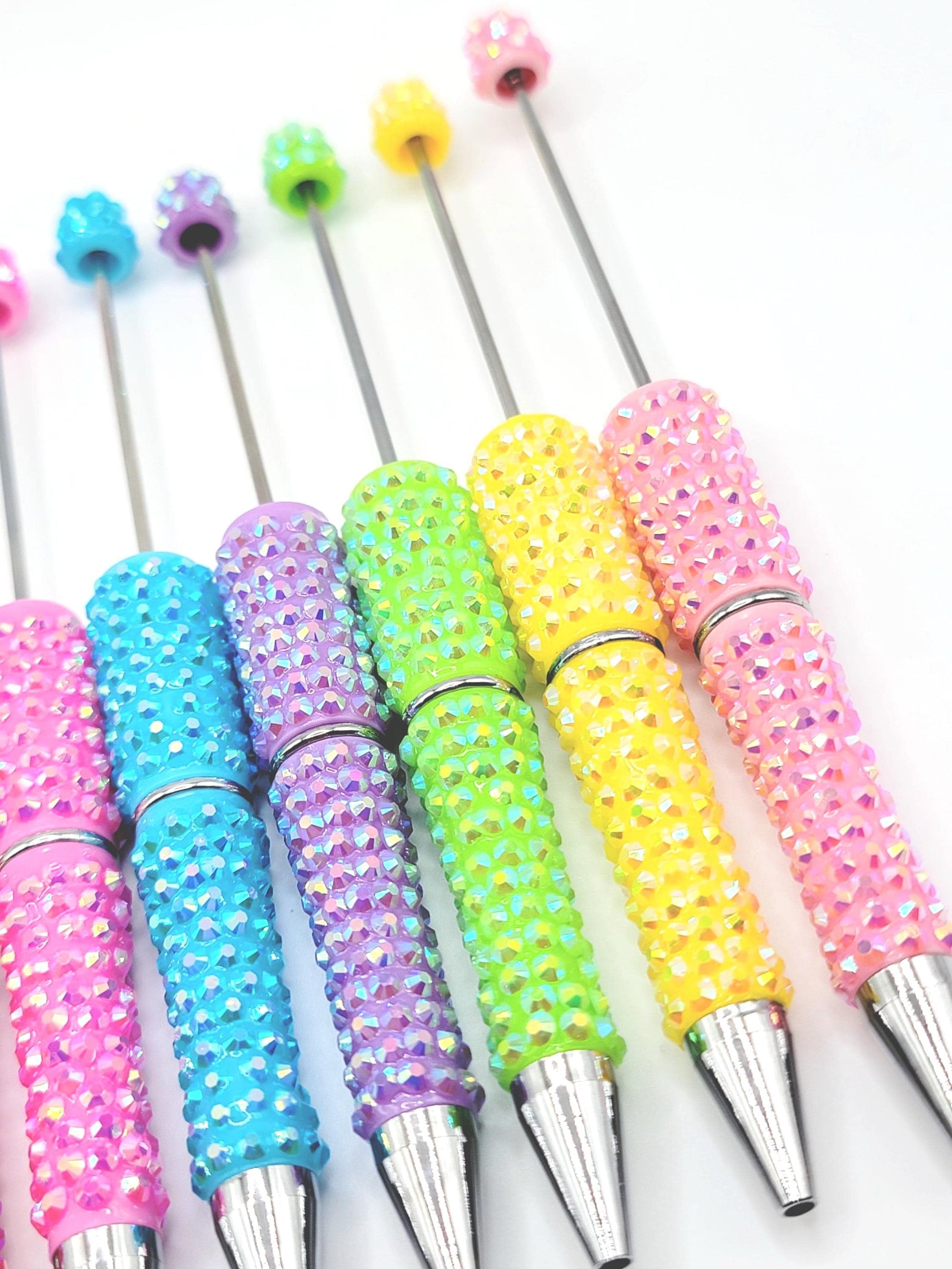 Colorful beaded pens with metallic accents on a white background