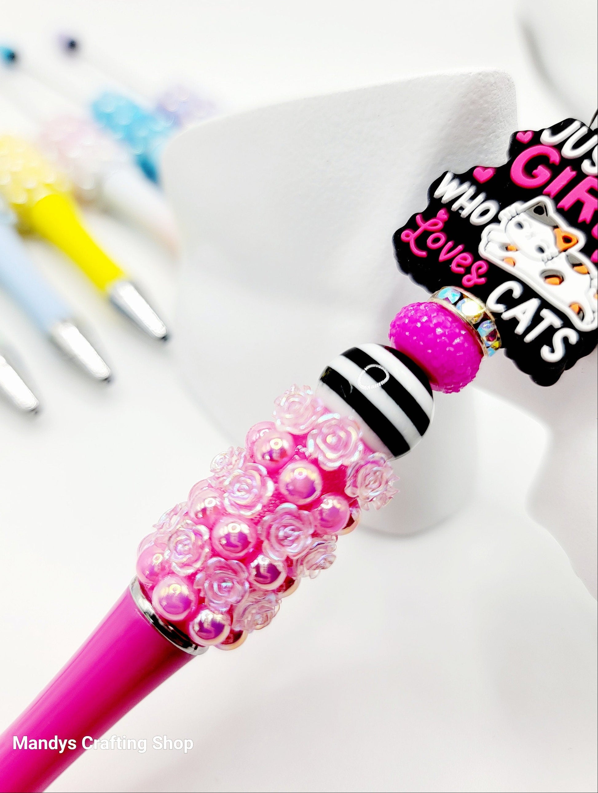 Pink beaded pen with a colorful character design on a white background