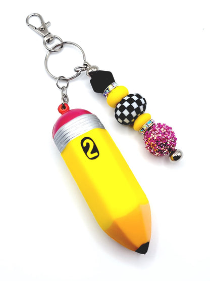 Yellow pencil-shaped keychain with decorative beads on a white background