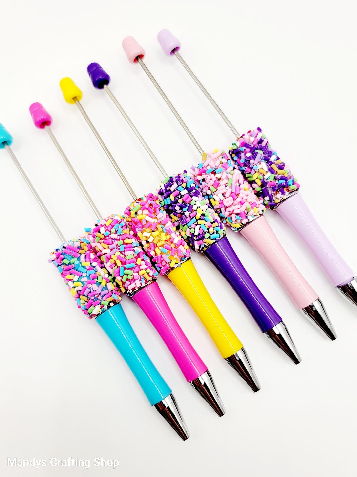Colorful pens with sprinkles on a white background