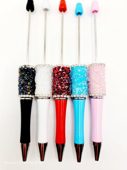 Five decorative pens with colorful glittery accents on a white background