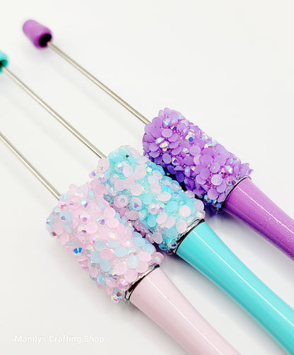 Three glittery pens with pastel colors on a white background