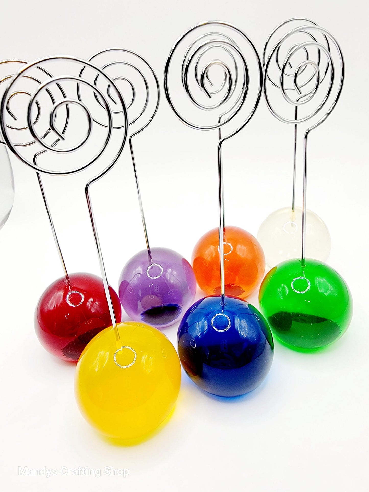 Colorful ball photo holders with decorative wire stems on a white background