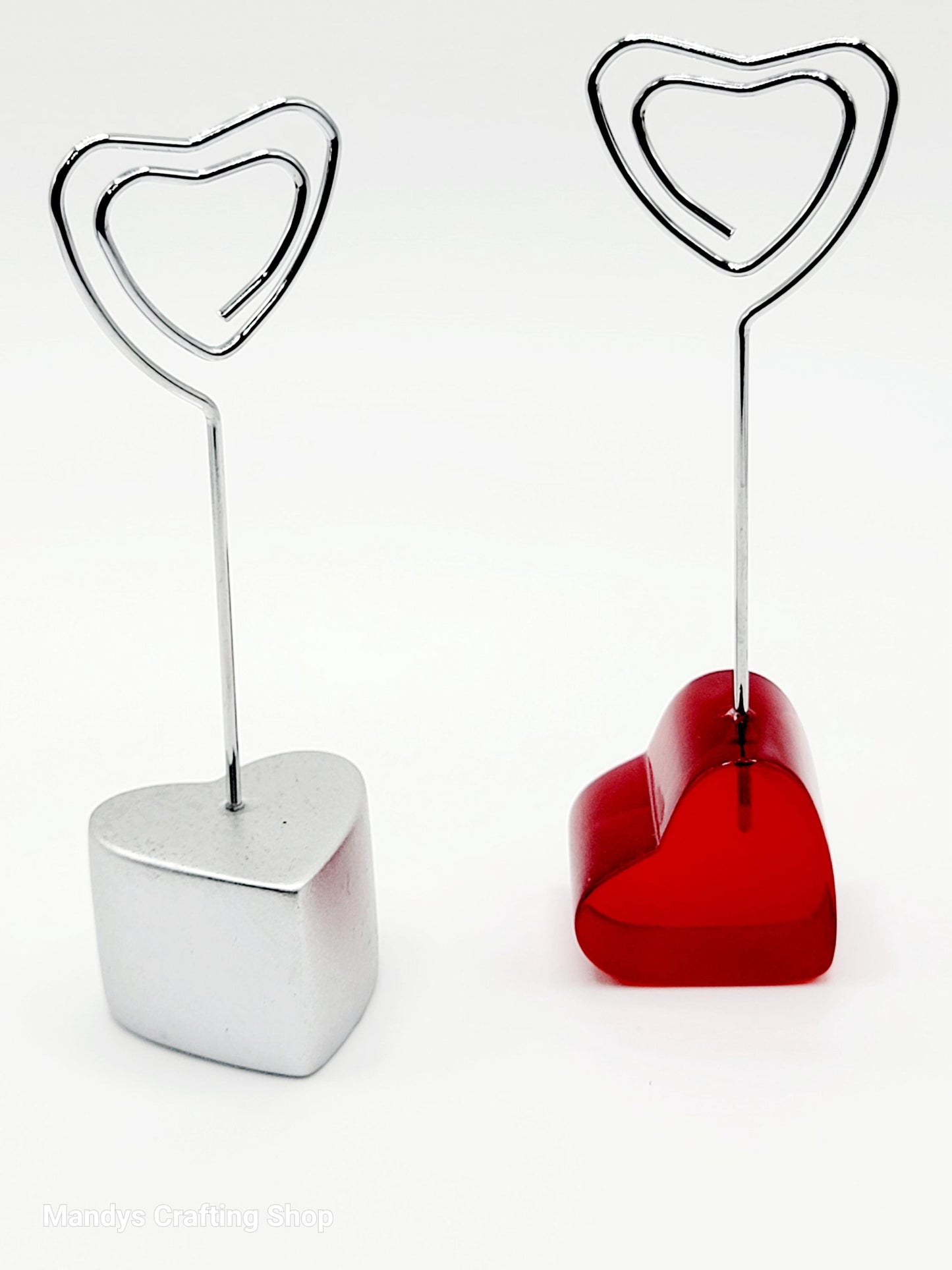 Two heart-shaped photo holders, one silver and one red, on a white background.