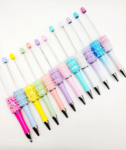 Colorful pens with decorative beads on a white background