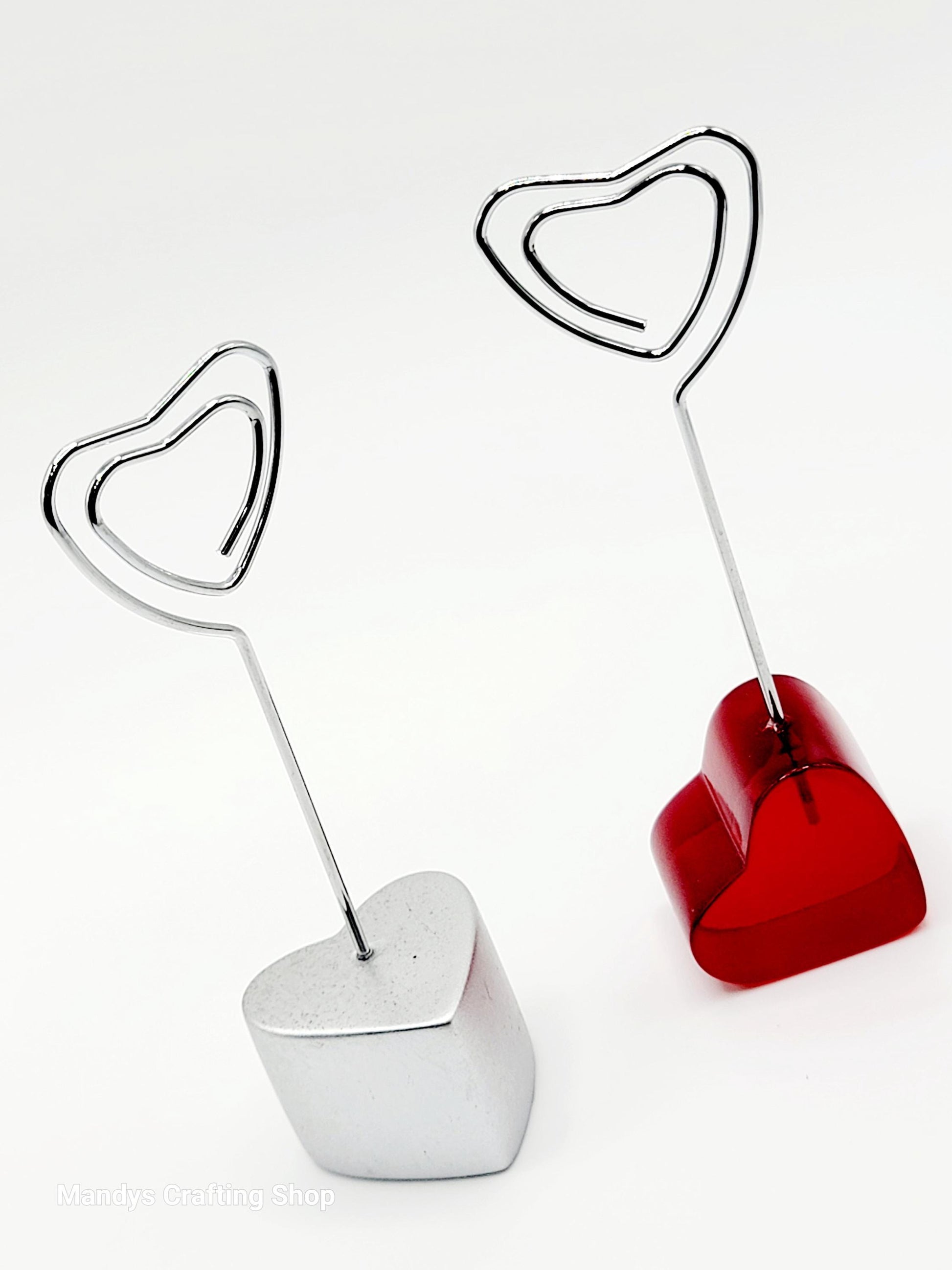Two heart-shaped photo holders, one red and one white, on a white background.