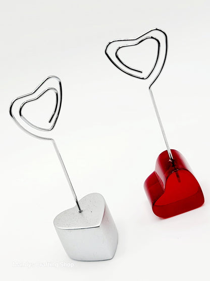 Two heart-shaped photo holders, one red and one white, on a white background.