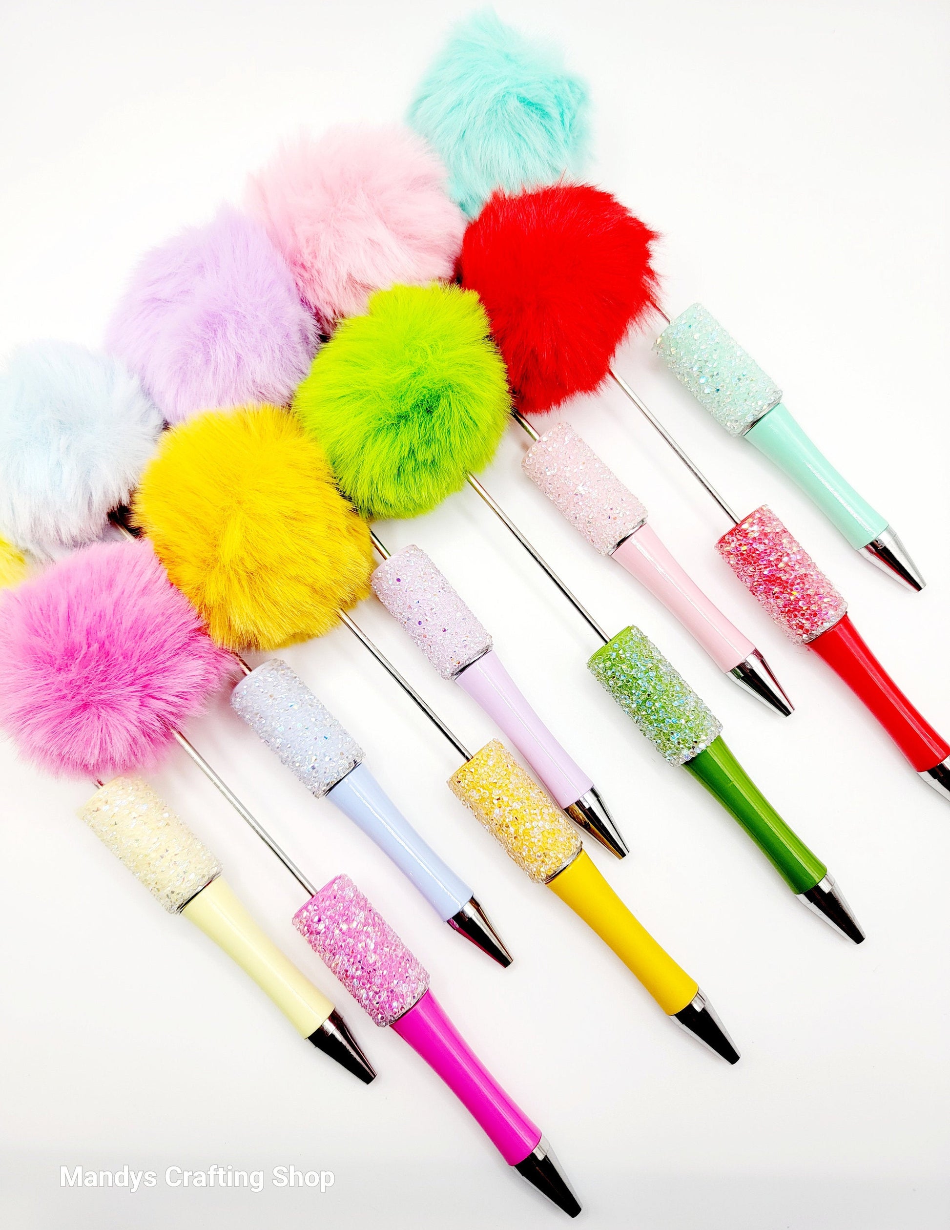 Colorful pens with pom-pom and glittery accents on a white background