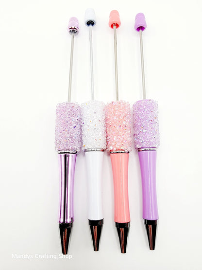 Four decorative pens with glittery accents on a white background