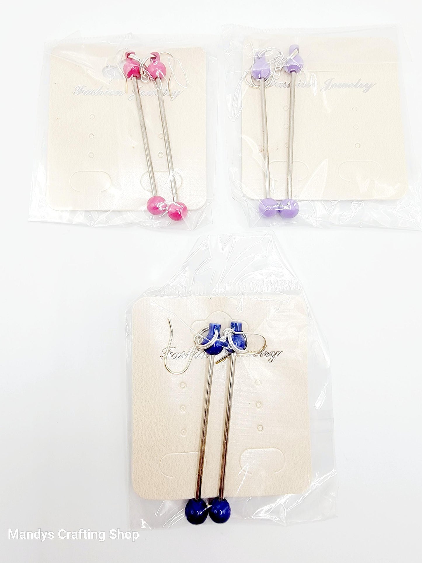 Set of three decorative sticks with colorful beads on a white background