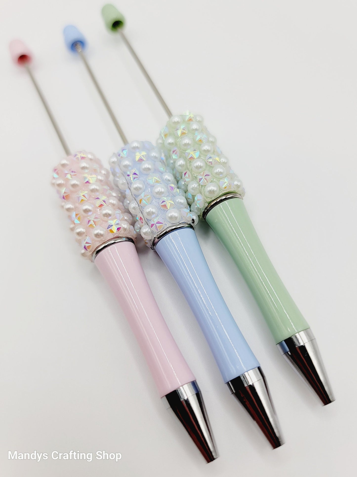 Three decorative pens with pastel colors and embellishments on a white background.
