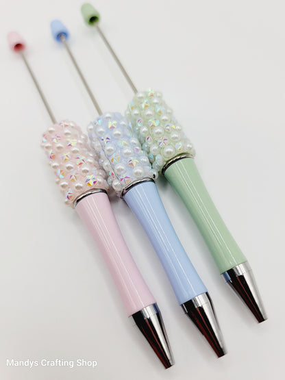 Three decorative pens with pastel colors and embellishments on a white background.