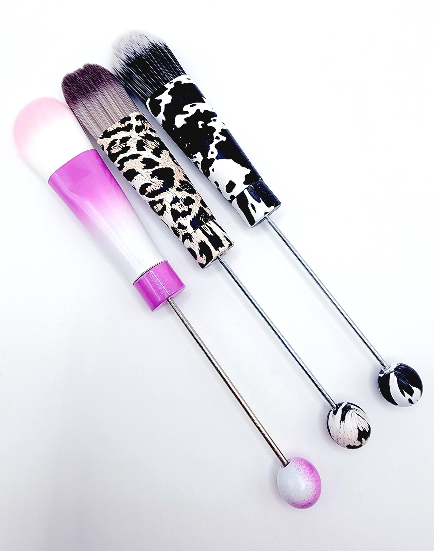 Three makeup brushes with leopard print handles on a white background