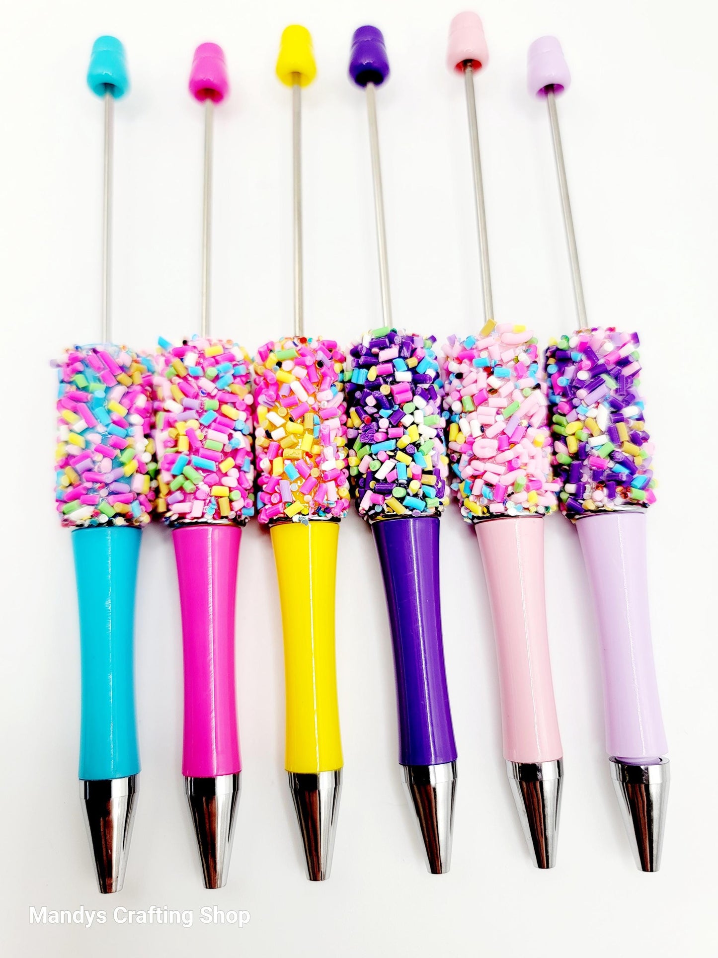 Colorful pens with sprinkles on a white background