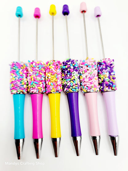 Colorful pens with sprinkles on a white background